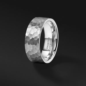 mens tungsten wedding band with a satin hammered texture standing in a gray room