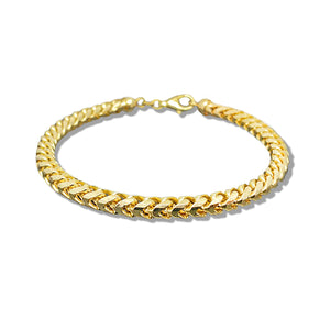 yellow gold franco link bracelet for women lying on a white surface