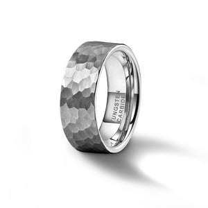 a tungsten carbide ring with a satin, hammered texture stands up on a white surface