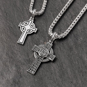 two celtic silver cross chains lie on a slate surface