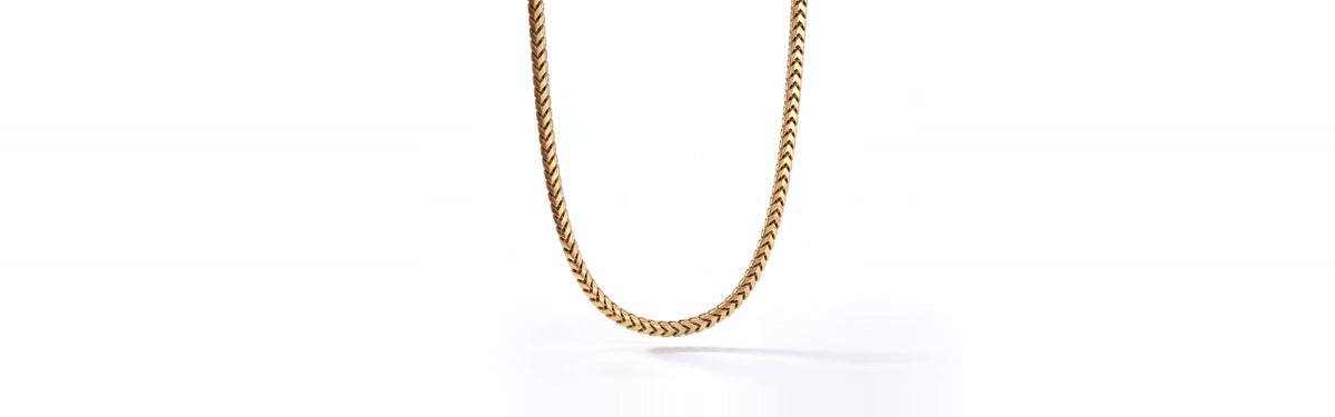 A solid yellow gold 4mm Franco chain hanging against a white background
