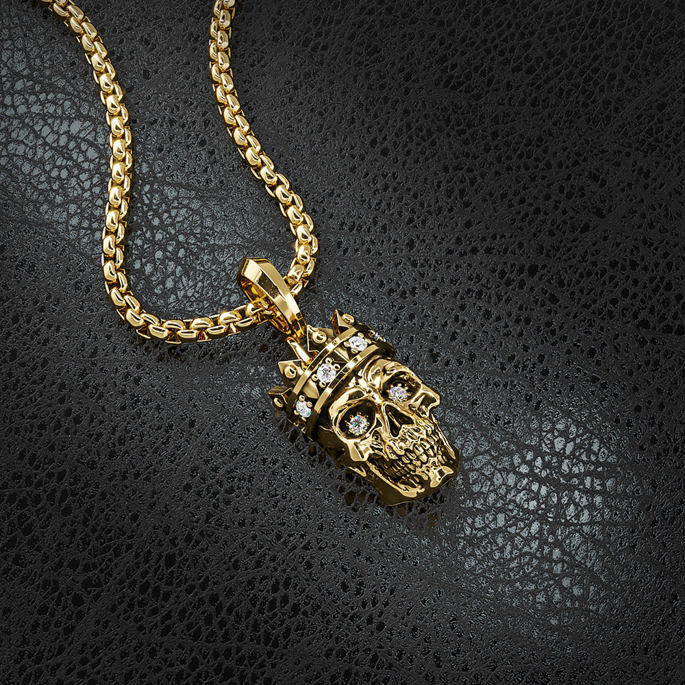 a gold skull pendant with diamonds lying on black leather