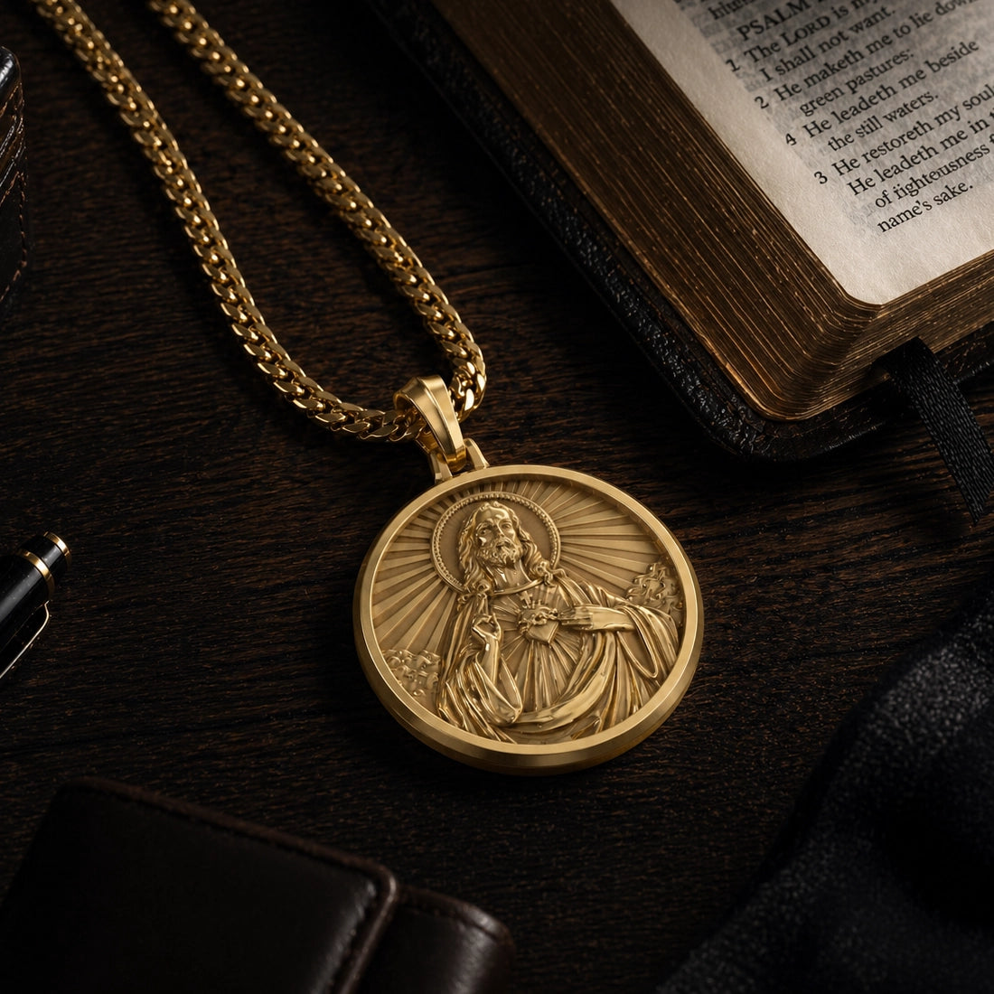 A gold sacred heart of Jesus pendant lays on a wood table near an open bible