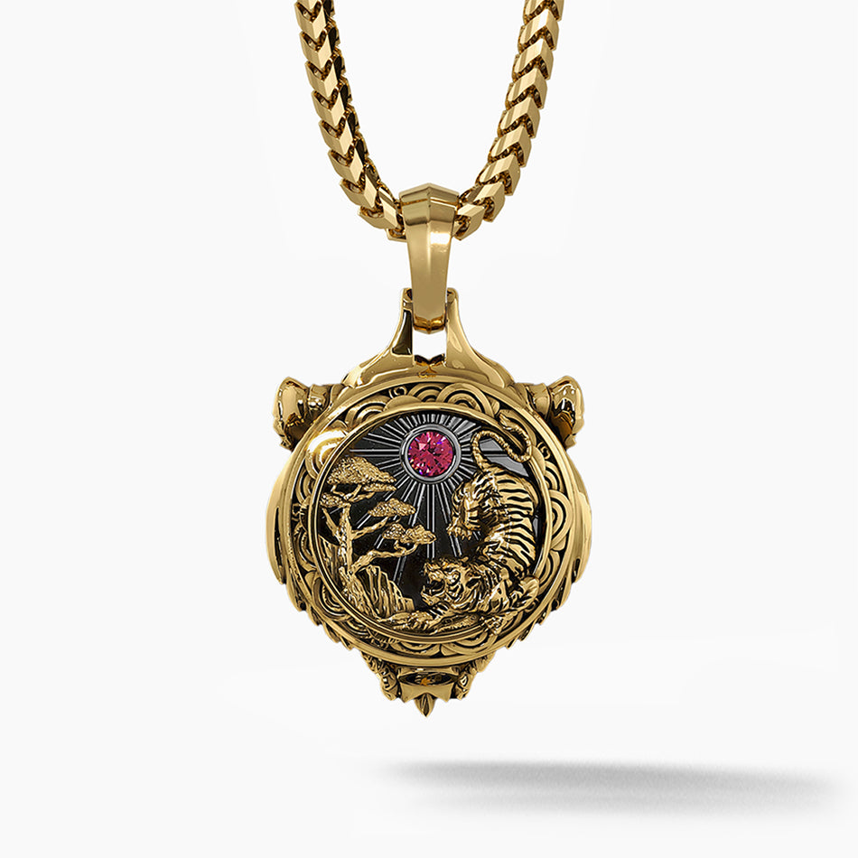 the back of a gold tiger pendant features a red diamond and a sculpted scene of trees and the sun