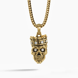 a mens gold pendant in the shape of a skull wearing a crown hangs from a necklace