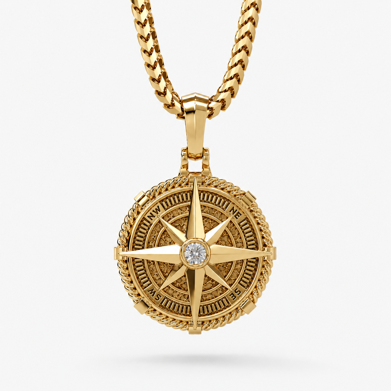 Gold Compass Pendant with a bezel set diamond in the middle hangs on a white background