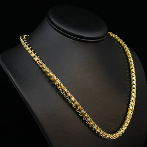 a thick 18 karat franco chain 6.5mm in width hangs on a black leather bust in a dark setting