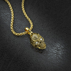 a gold sugar skull necklace lying on black leather