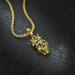 a gold skull pendant with diamonds lying on black leather