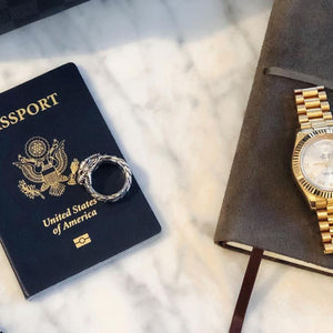 a silver dragon ring on a passport with a rolex