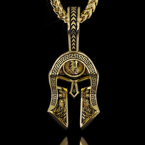 the back of a gold Spartan pendant shows two Spartan warriors carved into the helmet