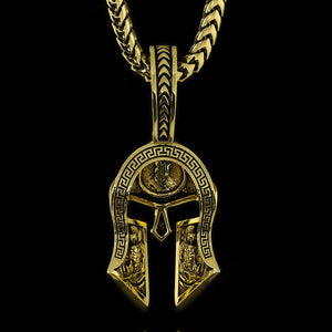 the back of a gold Spartan pendant shows two Spartan warriors carved into the helmet
