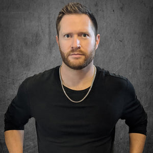 a man wearing a 14k white gold franco chain in a dark industrial room