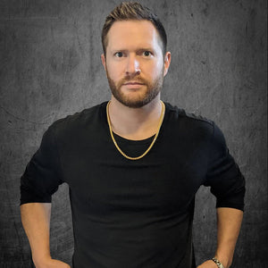 a man wearing an 18k yellow gold franco chain in a dark industrial room