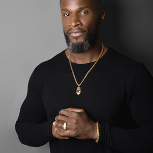 a man crossing his arms sports a gold wolf pendant and 14k franco bracelet