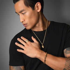 a man with his hand on his shoulder displays the polished gold bracelet he is wearing