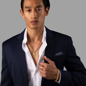 a stylish man wearing a blue suit wears a 5mm gold bracelet for men