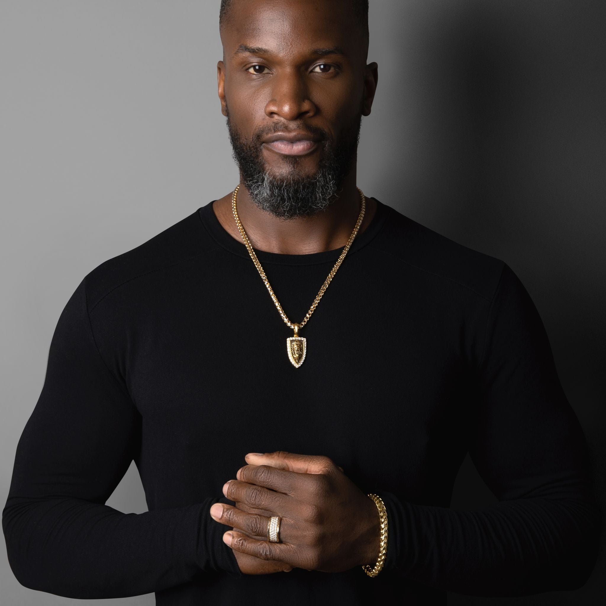 a muscular and stylish man wearing a black shirt and gold jewelry featuring a 6.5mm franco bracelet