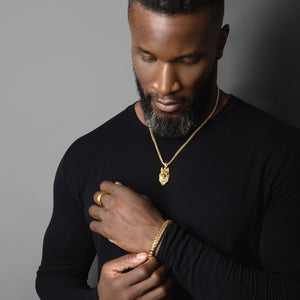 a man in a black shirt adjusts the 6.5mm 18 karat gold franco bracelet around his wrist