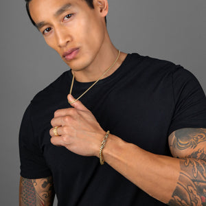 a handsome, tattooed man wearing gold jewelry including a gold bracelet, ring, and 3mm franco necklace