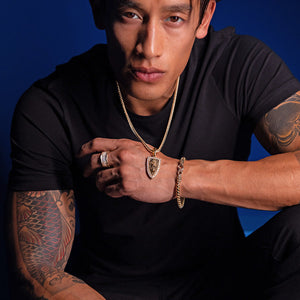 a man showcasing a gold jewelry set including a diamond pendant, diamond ring, and franco chain