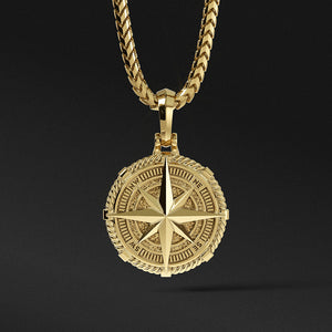 a detailed gold compass pendant hangs from a gold chain