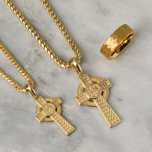 two Celtic gold necklaces crosses shine as they lie on a white marble surface
