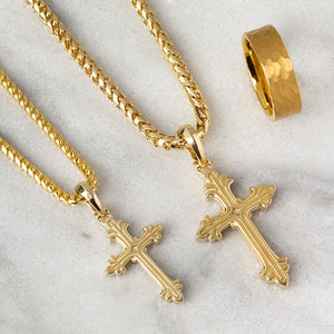 two gold necklaces crosses shine as they lie on a white marble surface