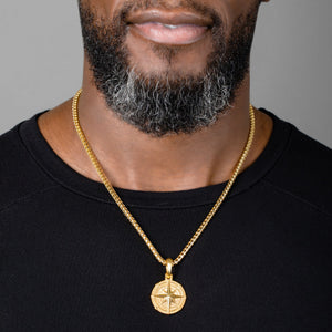 a large gold compass pendant hangs from a mens necklace