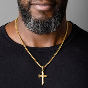 man wears a large gold cross necklace and franco chain