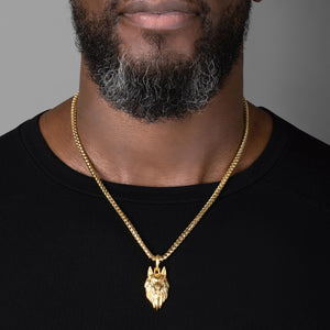 a large gold wolf pendant hangs from a mans necklace