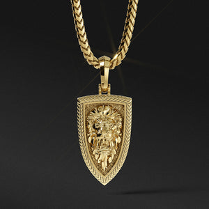 a gold lion head pendant is sculpted into the shape of a shield with a pattern around the border