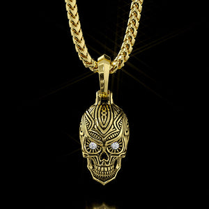 a gold sugar skull pendant hanging on a franco chain