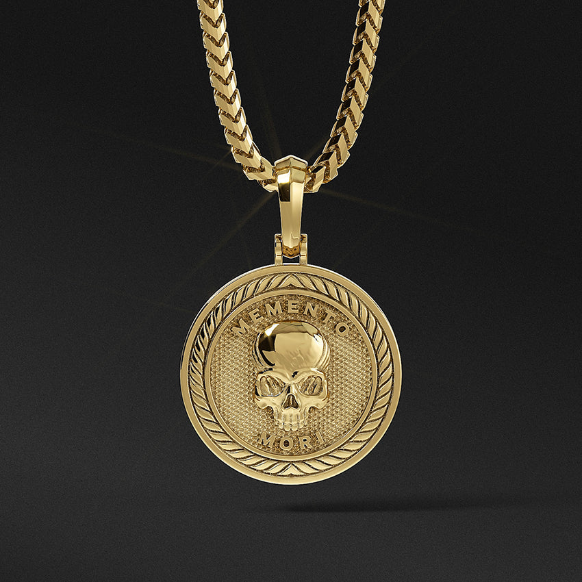 a gold skull pendant in the shape of a medallion with the words memento mori inscribed