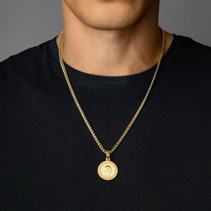 a man in a black shirt wearing a gold necklace and small gold skull pendant