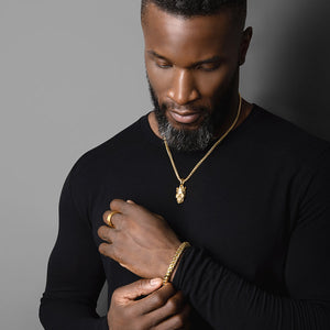 a man wears a polished gold skull pendant and matching gold bracelet