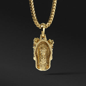The back of a gold skull pendant shows a throne carved into the metal