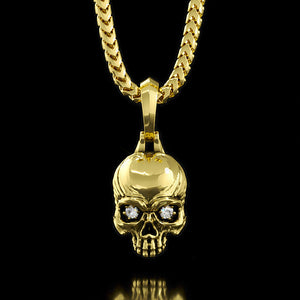 a gold skull pendant with diamond eyes hangs from a necklace