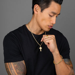 an active man adjusts his 14 karat gold cross pendant as it hangs from a franco necklace