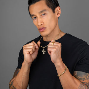 a fit man holds up the gold cross pendant he's wearing which shines as it hangs from a necklace