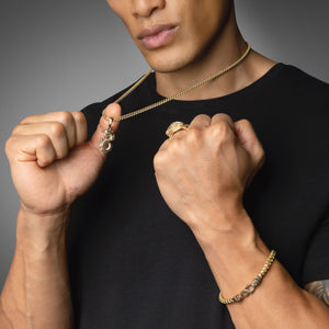 a tattooed man shows off his dragon necklace and ring, made from solid gold