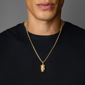 a man in a black shirt wearing a gold necklace and small skull pendant