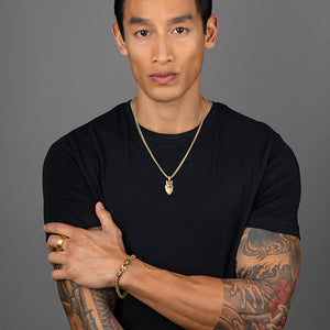 an active man in a black shirt wears a gold crown ring and wolf necklace