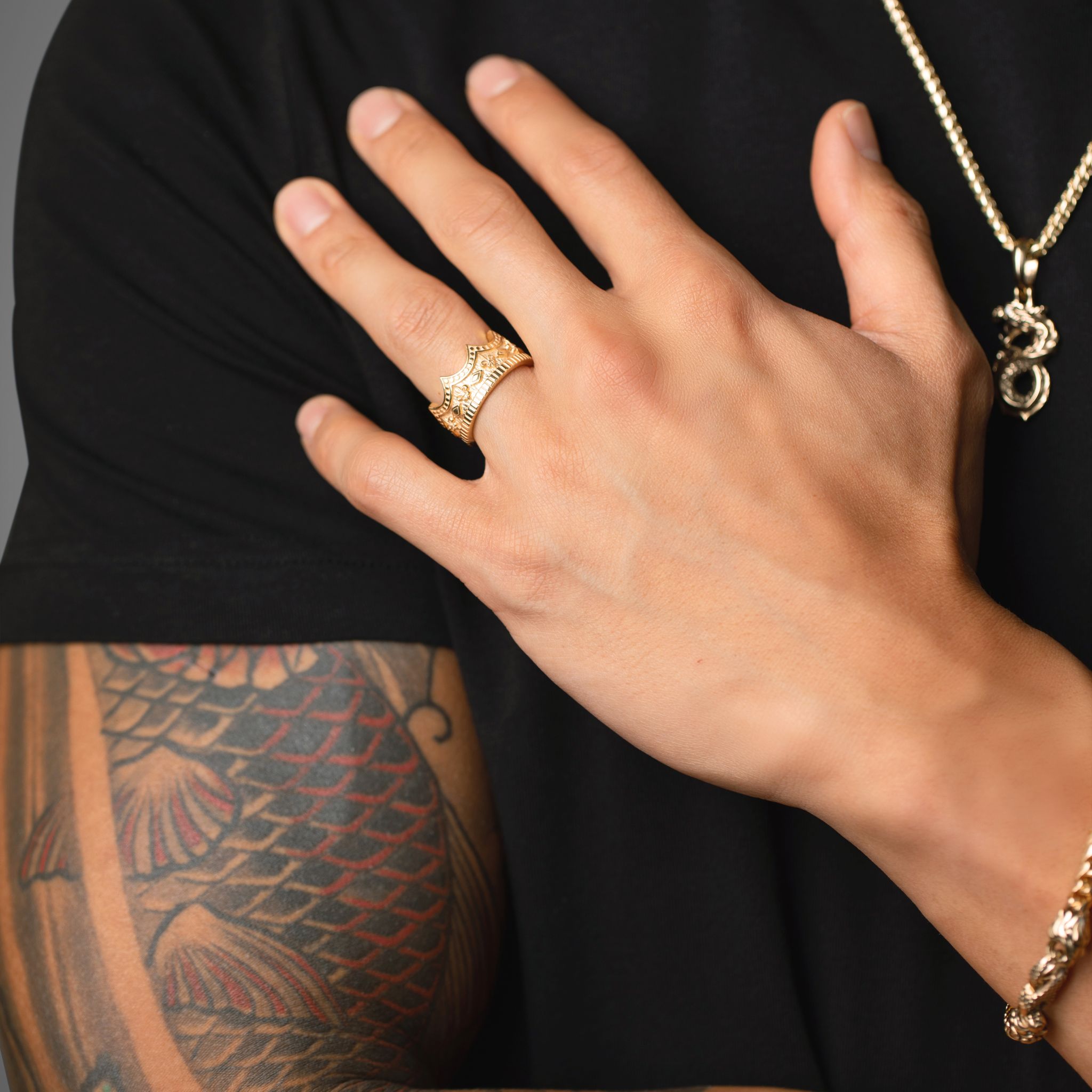 man in a black shirt poses to show off his 14 karat gold crown ring