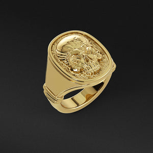 a poished skull signet ring standing on a black surface