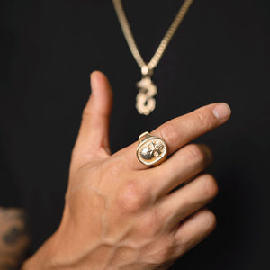 a close up view of a gold skull ring on a man's hand