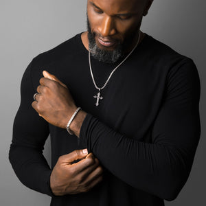 a man in a black shirt adjusts his sleeve while showing off his mens silver bracelet