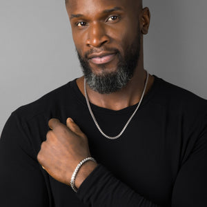 a close in photo of a man in a black shirt wearing silver franco jewelry that is shining