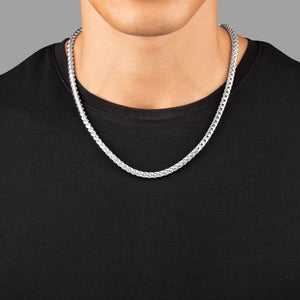 a close view of a man in a black shirt wearing a 5mm silver franco chain