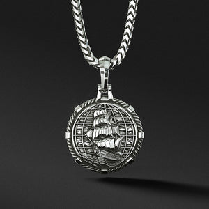 The back of a silver pendant features a nautical ship and globe
